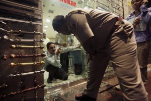一名警察在在达德拉，孟买，印度，7月13日发生爆炸的现场询问店主2011年三是上下班高峰协调爆炸造成20人死亡和131人受伤多;没有组已经对袭击事件负责。©美联社照片/ Rajanish Kakade